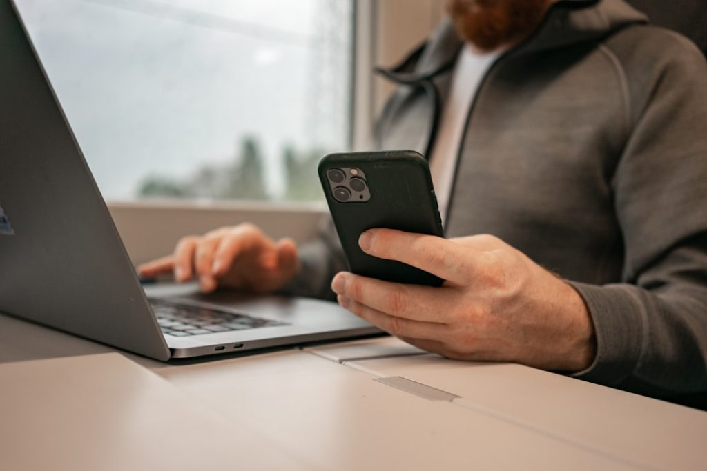 Male hands are typing on a laptop while traveling by train. Phone in hand, remote work, businessman on a trip